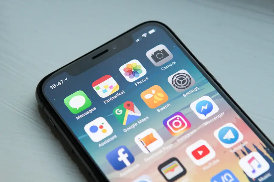 Android phone showing a grid of app icons on a wooden table