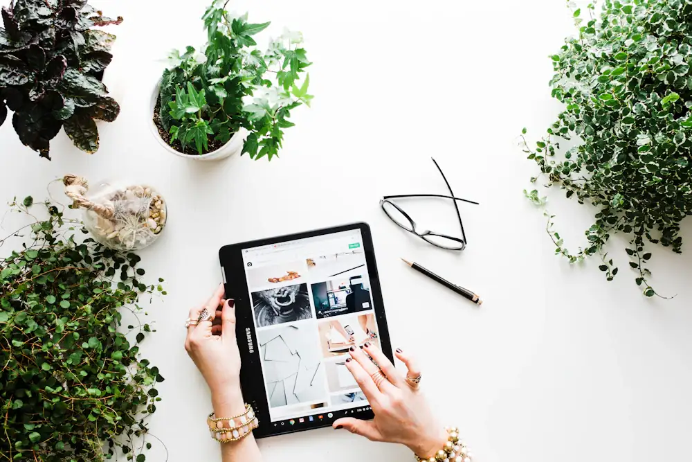 Tablet on a white desk surrounded by houseplants during a review write-up